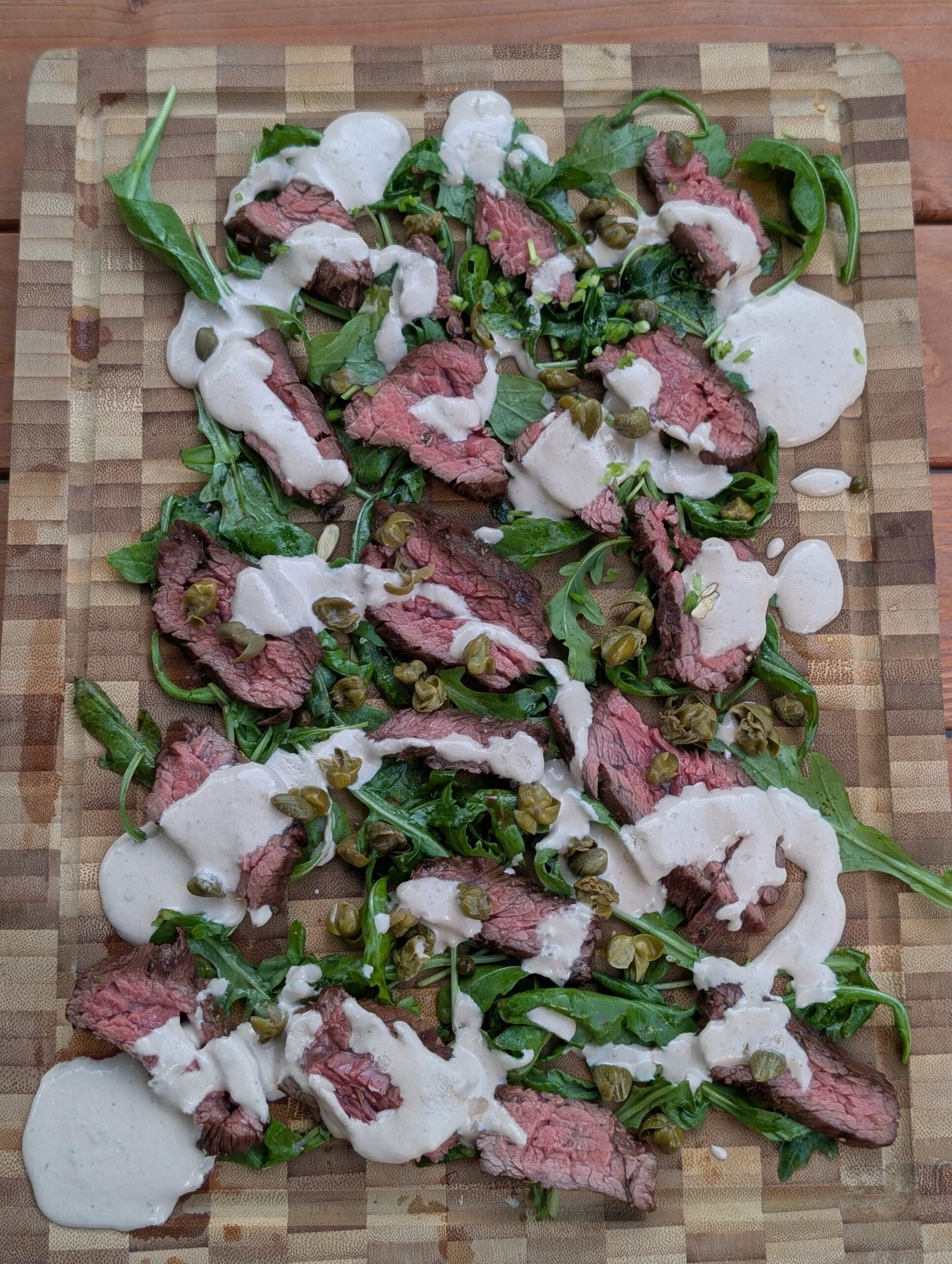 Steak tonnato van bavette met tonijnsaus en kappertjes op serveerplank