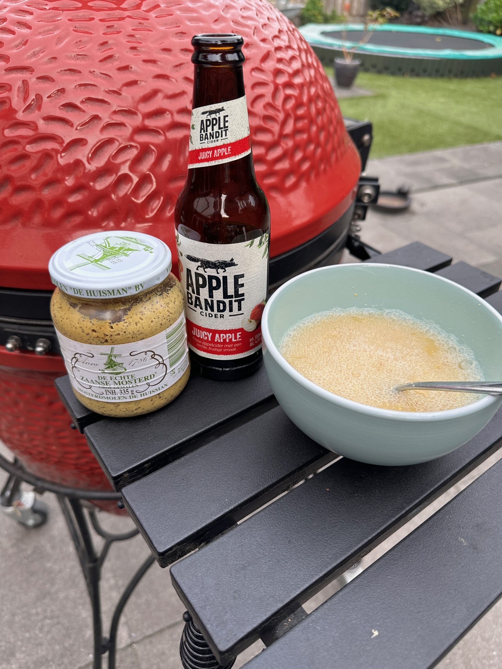 Zelfgemaakte cider-mosterdsaus in pannetje naast kamado grill