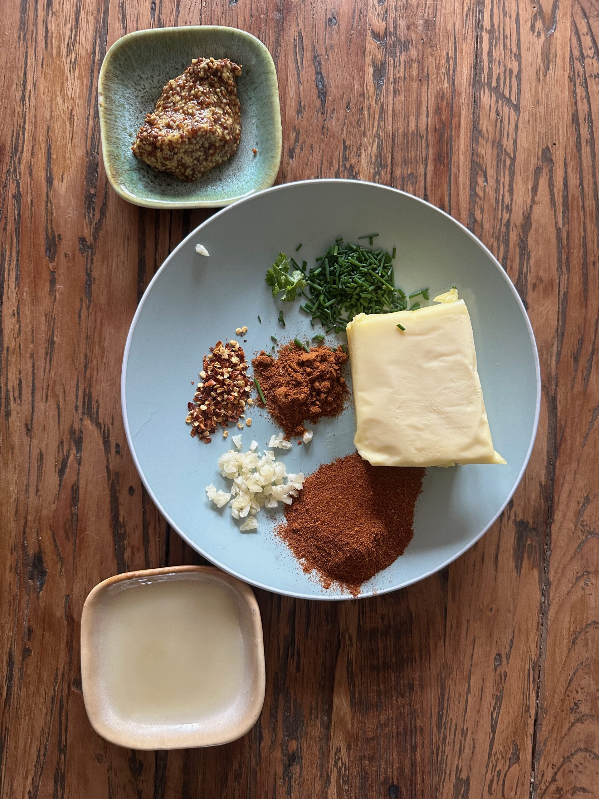 Ingrediënten voor gegrilde entrecote met citroen-knoflookboter uitgestald op houten snijplank