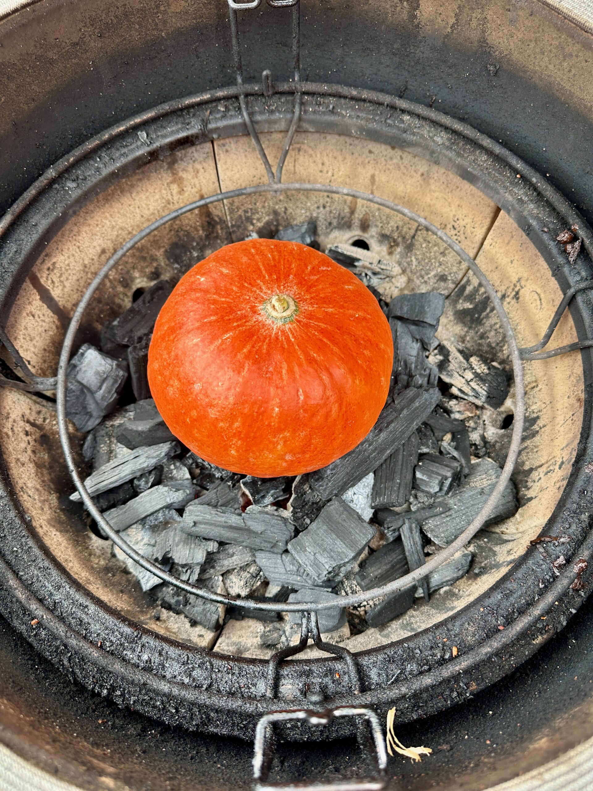 Gegrilde pompoen direct tussen BBQ kolen caveman-stijl