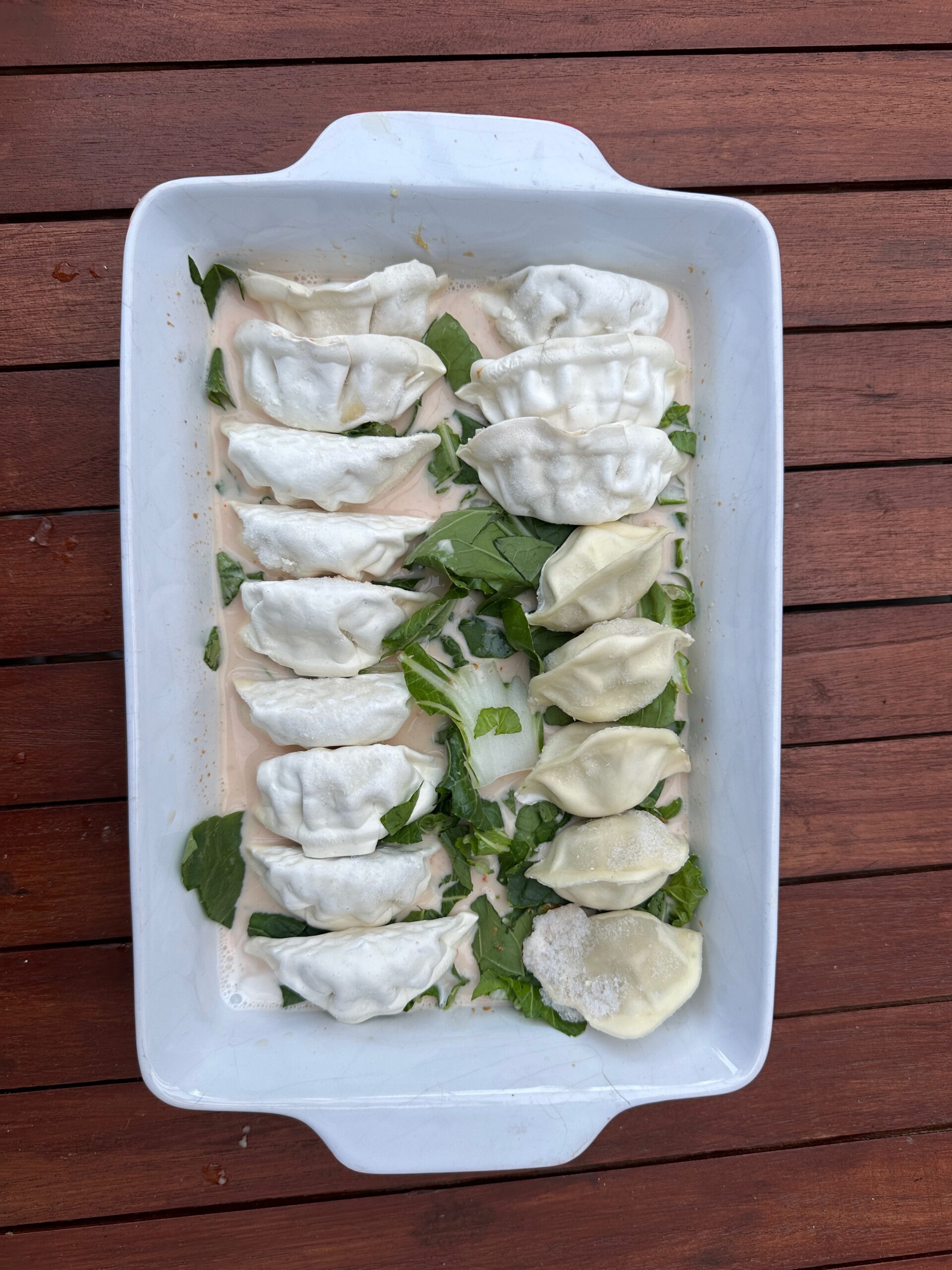 Bevroren gyoza dumplings geplaatst op paksoi in ovenschaal voor kamado BBQ
