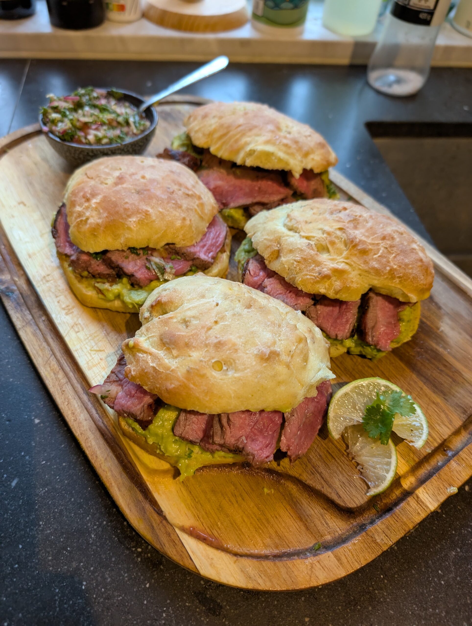 Gegrilde steak op zelfgemaakt maisbroodje met guacamole en ingelegde rode ui